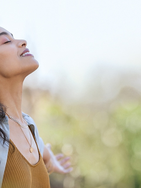 Young woman with arms outstretched breathing in.