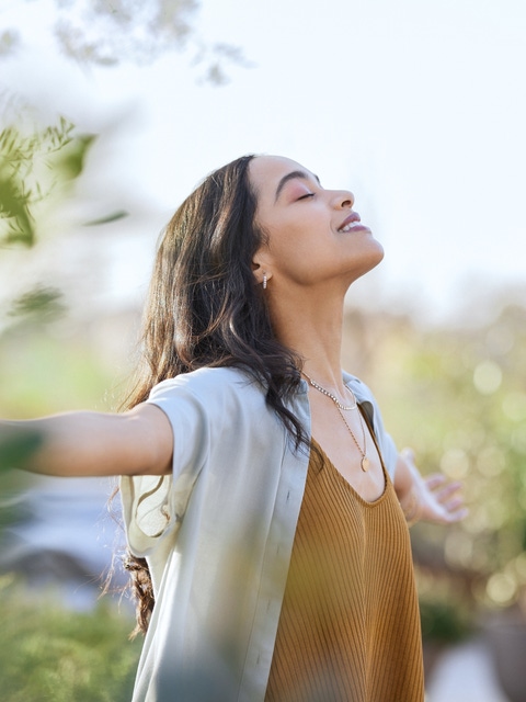 Young woman with arms outstretched breathing in.