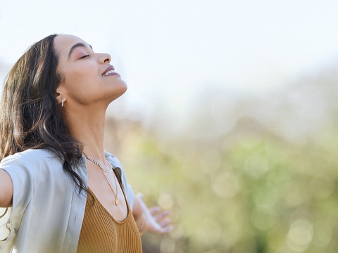 Young woman with arms outstretched breathing in.